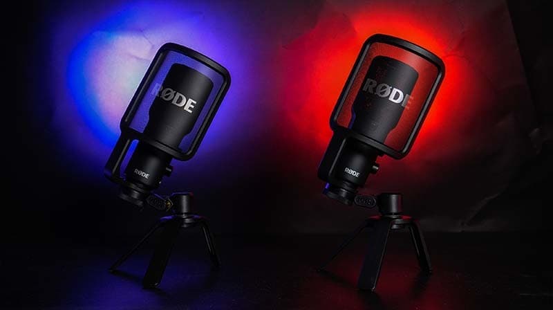 A RODE NT-USB+ (left) & the RODE NT-USB side by side. A blue light illuminates the RODE NT-USB+ and a red light illuminates the RODE NT-USB.