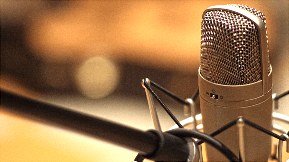 A zoomed in photograph of a silver microphone in a mic desk stand.