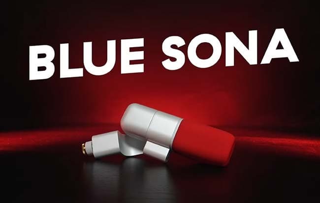 Image shows a white Blue Sona microphone with a red muff, placed on a table. The microphone is lit with a red spotlight against a dark background and has white, capitalised text running diagonally across the image that reads: BLUE SONA
