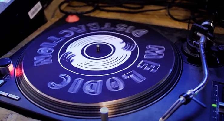 A vinyl turntable with a slip mat that reads "Melodic Distraction"